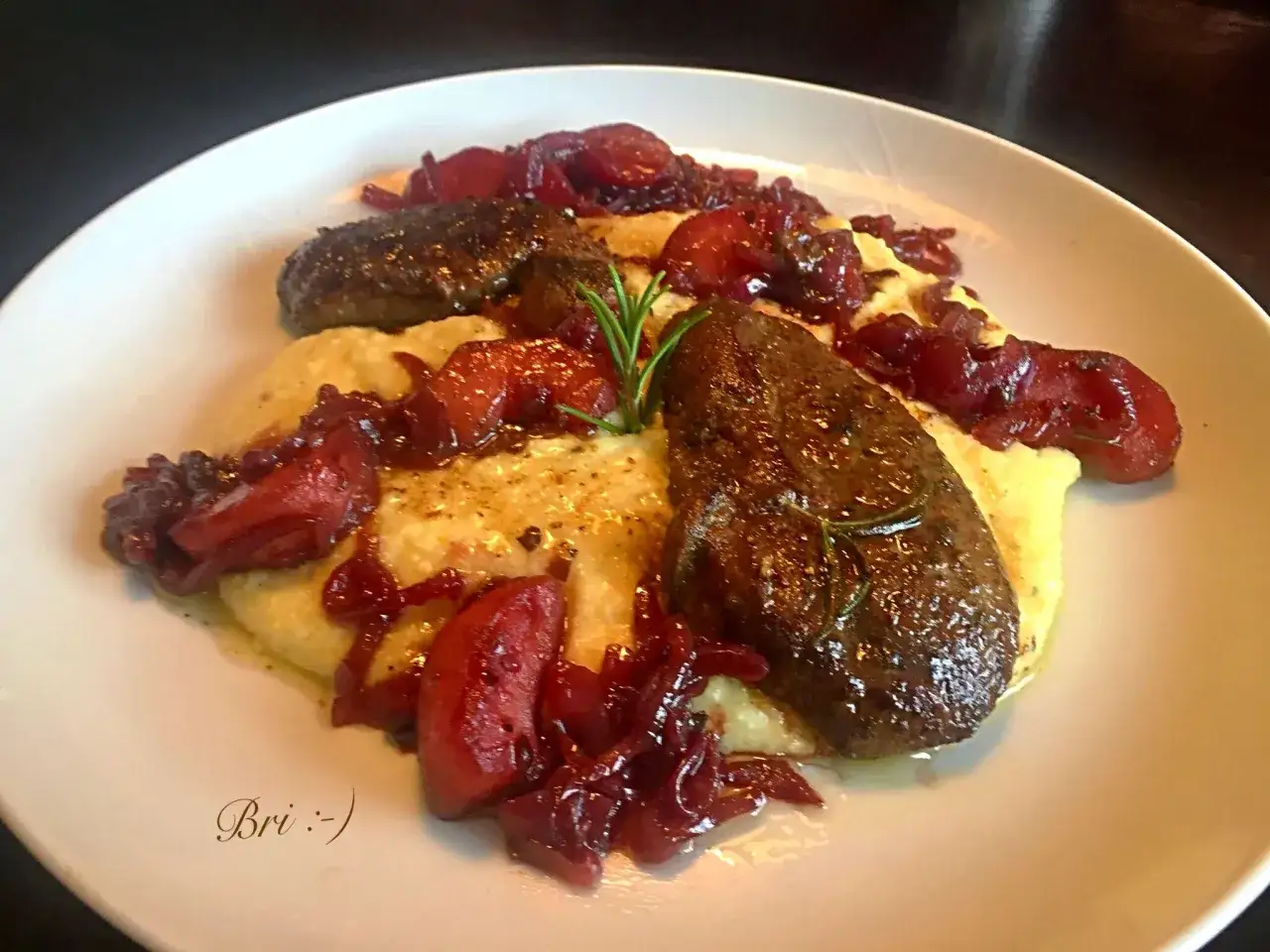 Rehleber zubereiten: Gebratene Rehleber mit cremigem Polenta und karamellisierten roten Zwiebeln, garniert mit Rosmarin.