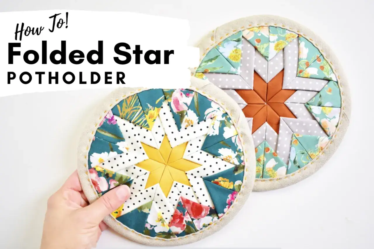 Hand holding a folded star potholder with a yellow center. Another folded star potholder with an orange center is behind it.