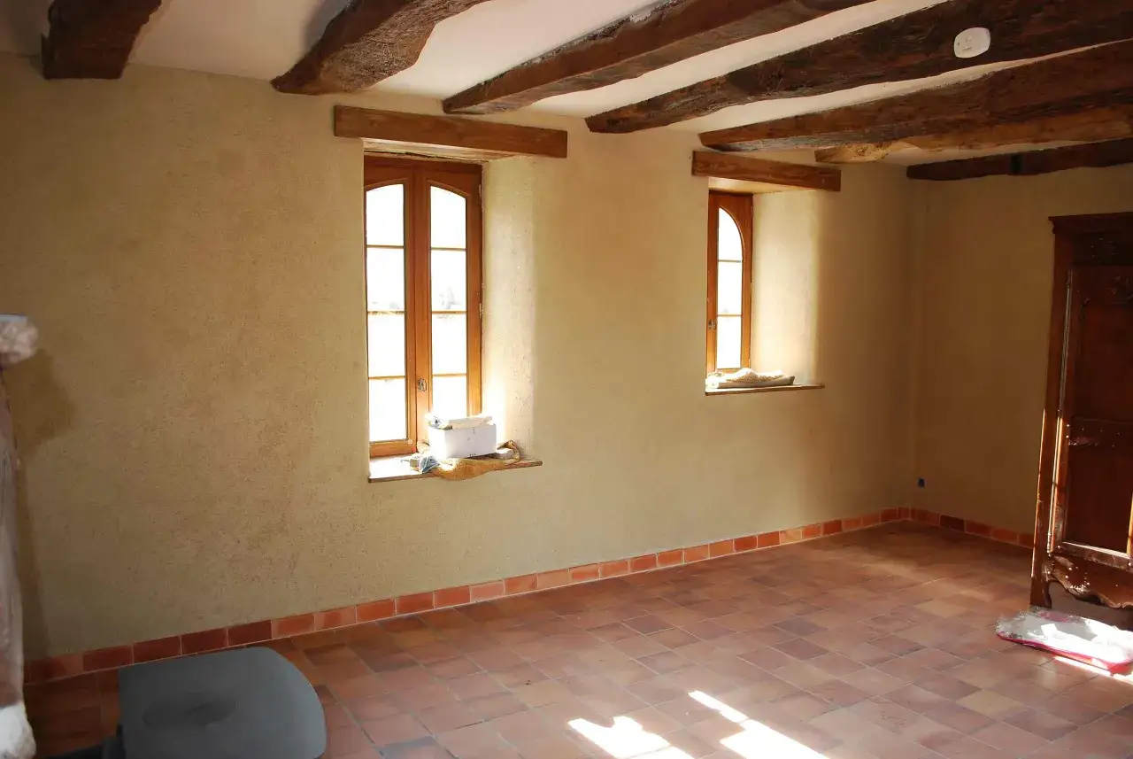 Murs en enduit chaux chanvre finition lisse, poutres apparentes, deux fenêtres en bois, sol en tomettes.