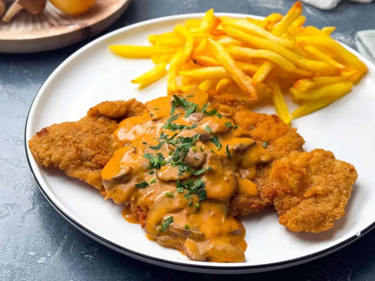Knuspriges Schnitzel mit cremiger Champignon-Rahm-Sauce und Pommes Frites. Ein Klassiker, der immer schmeckt.