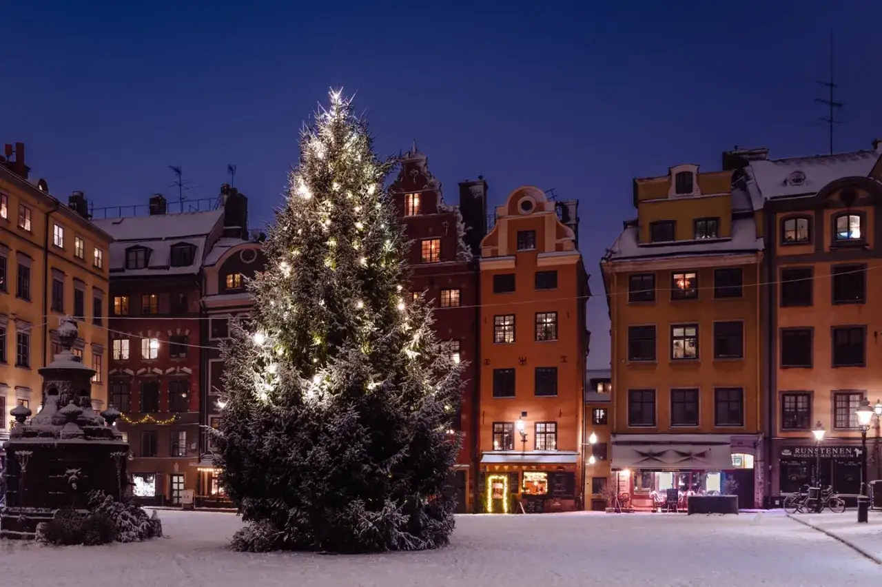 Snötäckt torg med julgran och gamla hus i Stockholm. En magisk julafton i Gamla Stan.