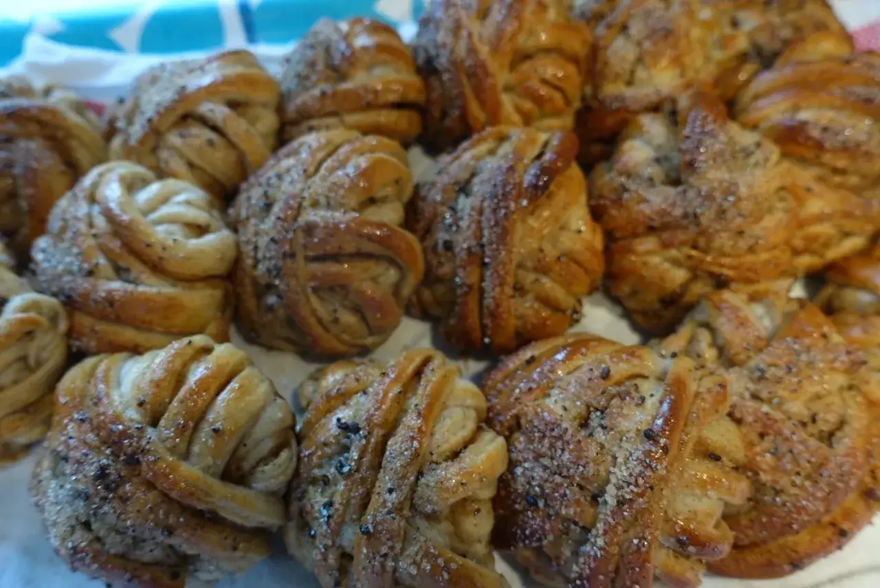 En hög med gyllene tekakor med kardemumma, strösslade med socker och kardemummakärnor.