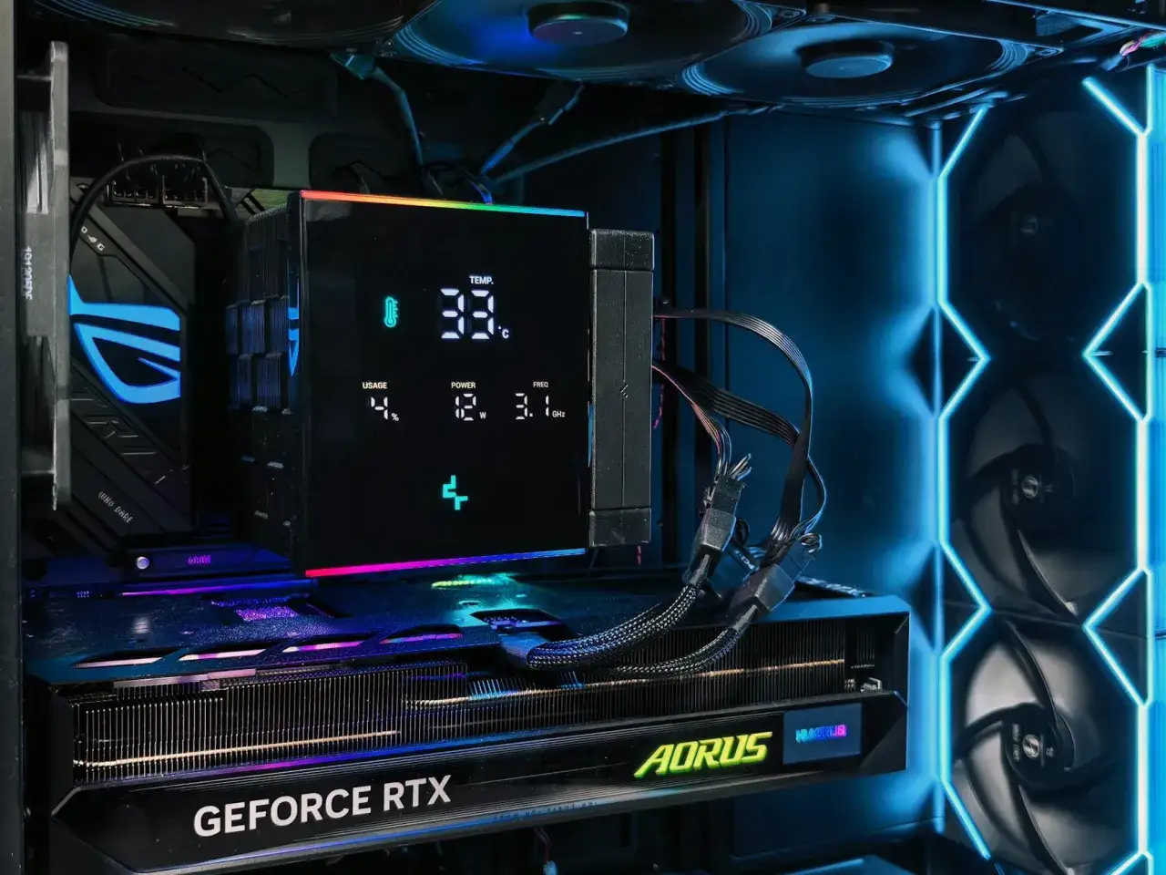 Wnętrze obudowy komputera z podświetlaną kartą graficzną GeForce RTX i chłodzeniem procesora z wyświetlaczem pokazującym temperaturę.
