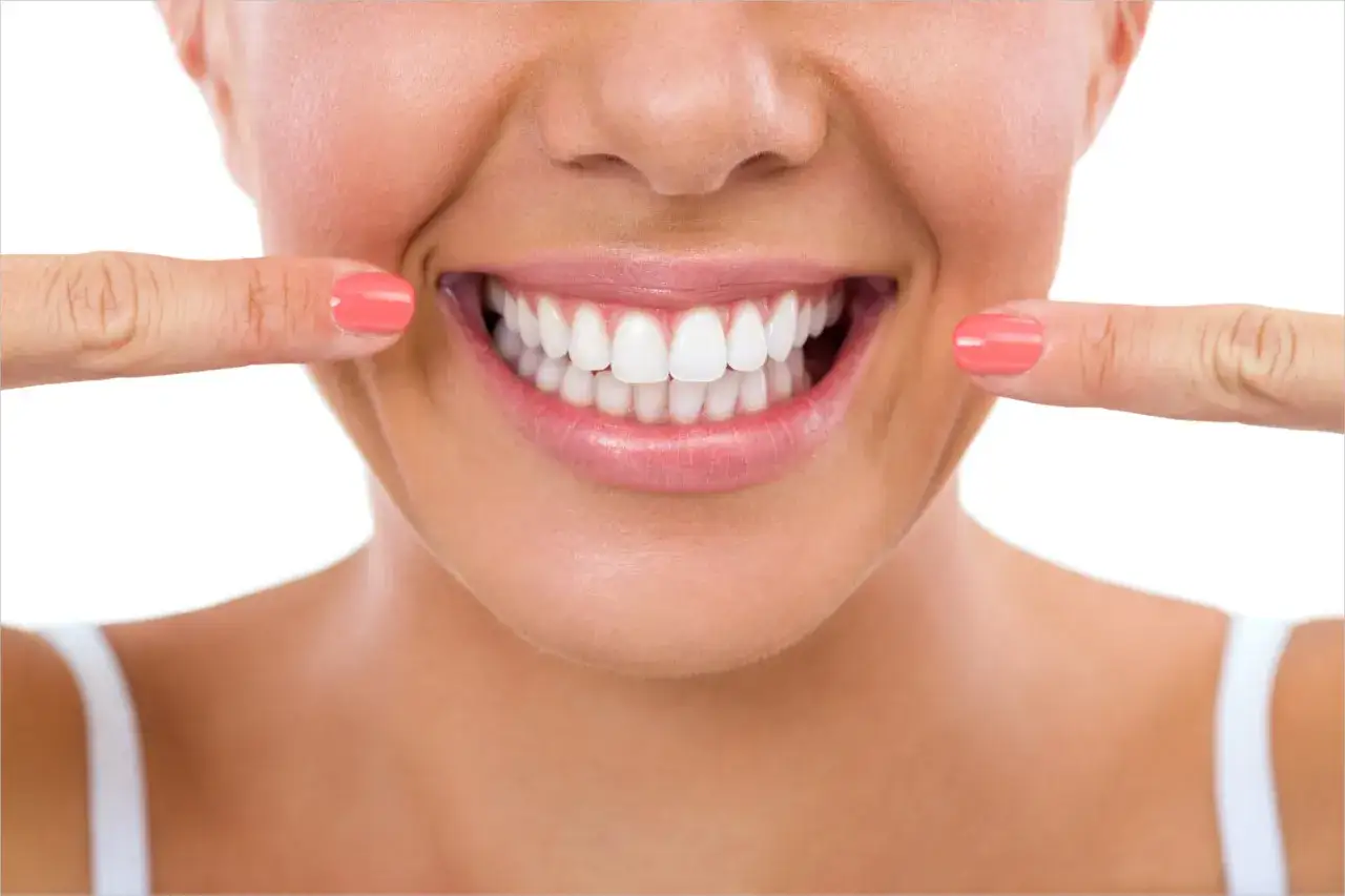 Sorriso smagliante con dita che indicano i denti bianchi, un invito a lavarsi i denti subito dopo mangiato per un alito fresco.