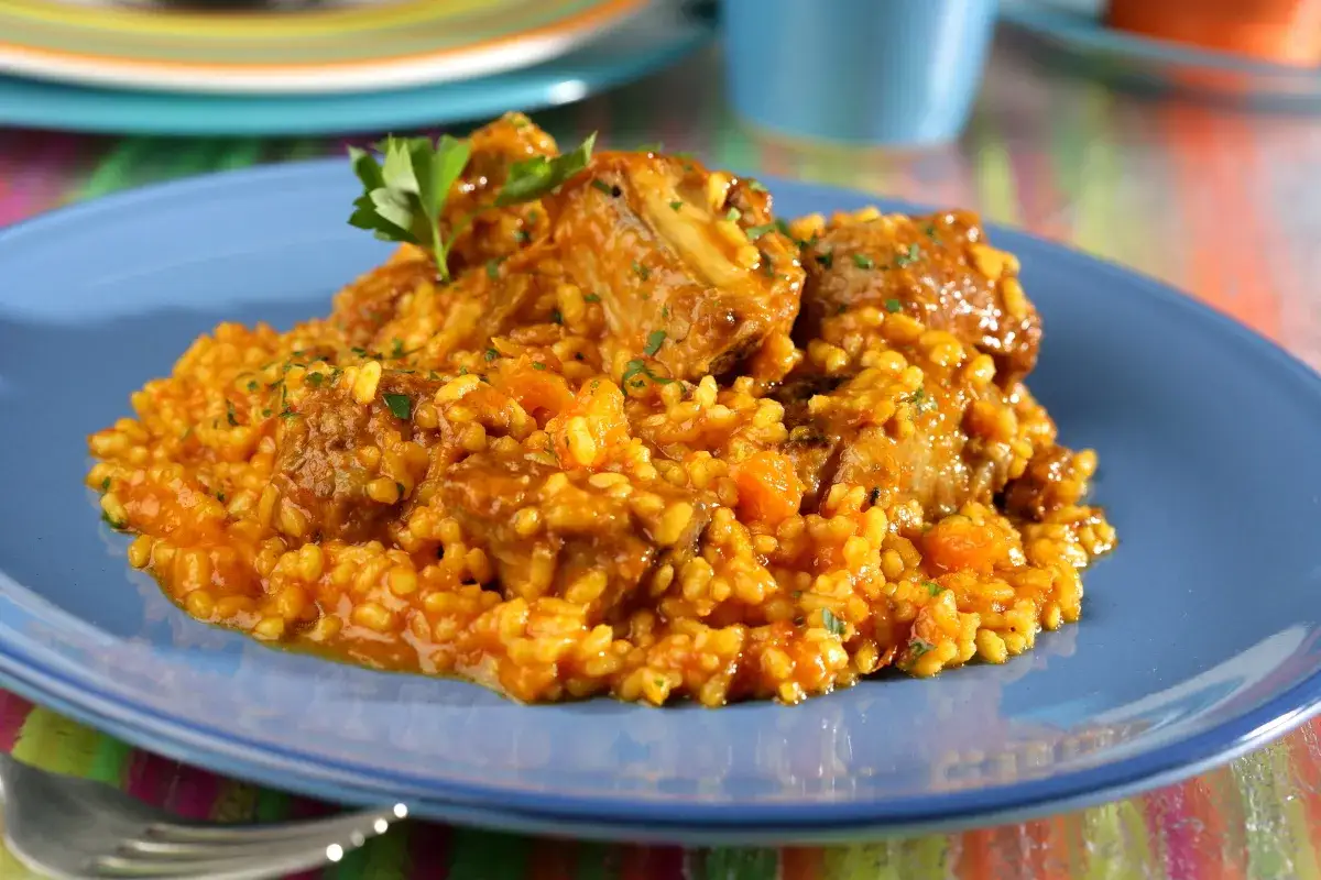 Un plato de arroz con costillas, adornado con perejil fresco.