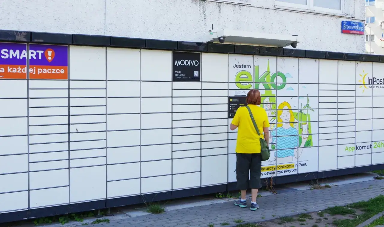 Kobieta odbiera paczkę z paczkomatu InPost. Wygodna opcja dla zakupów z Allegro.