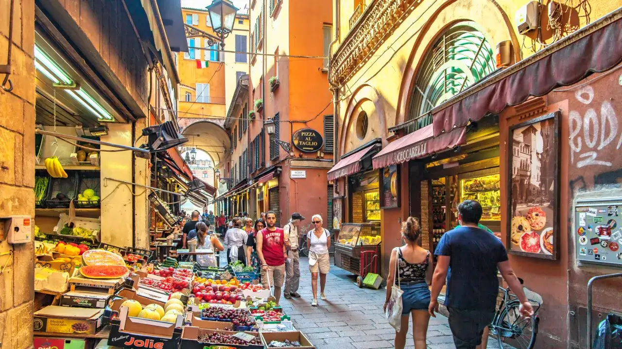 En livlig marknadsgata i Emilia Romagna, Italien, med fruktstånd och butiker.