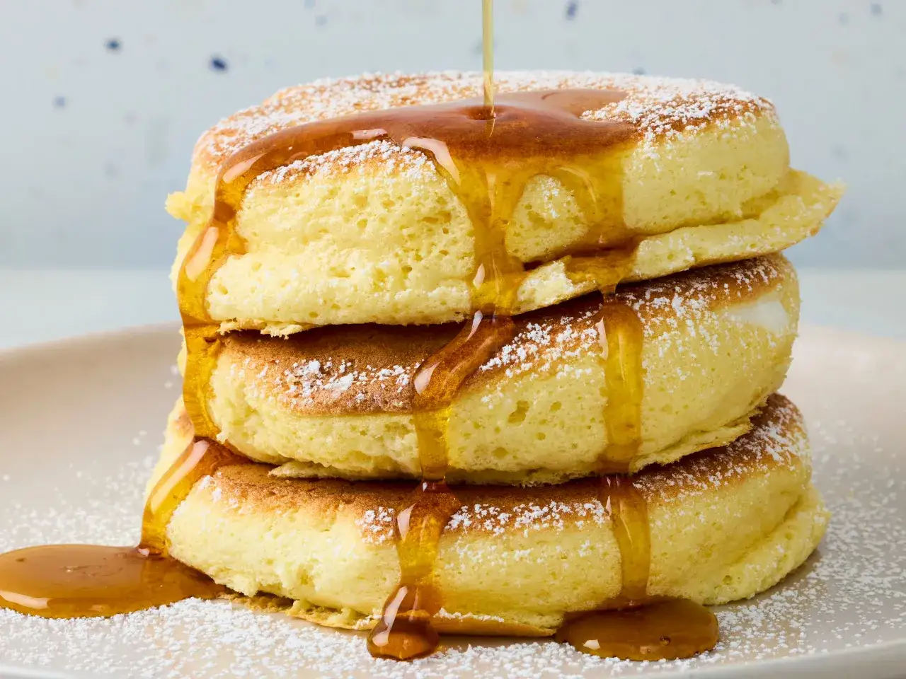 Fluffige japanische Pancakes, best&auml;ubt mit Puderzucker und &uuml;bergossen mit goldenem Sirup, ein s&uuml;&szlig;er Genuss.