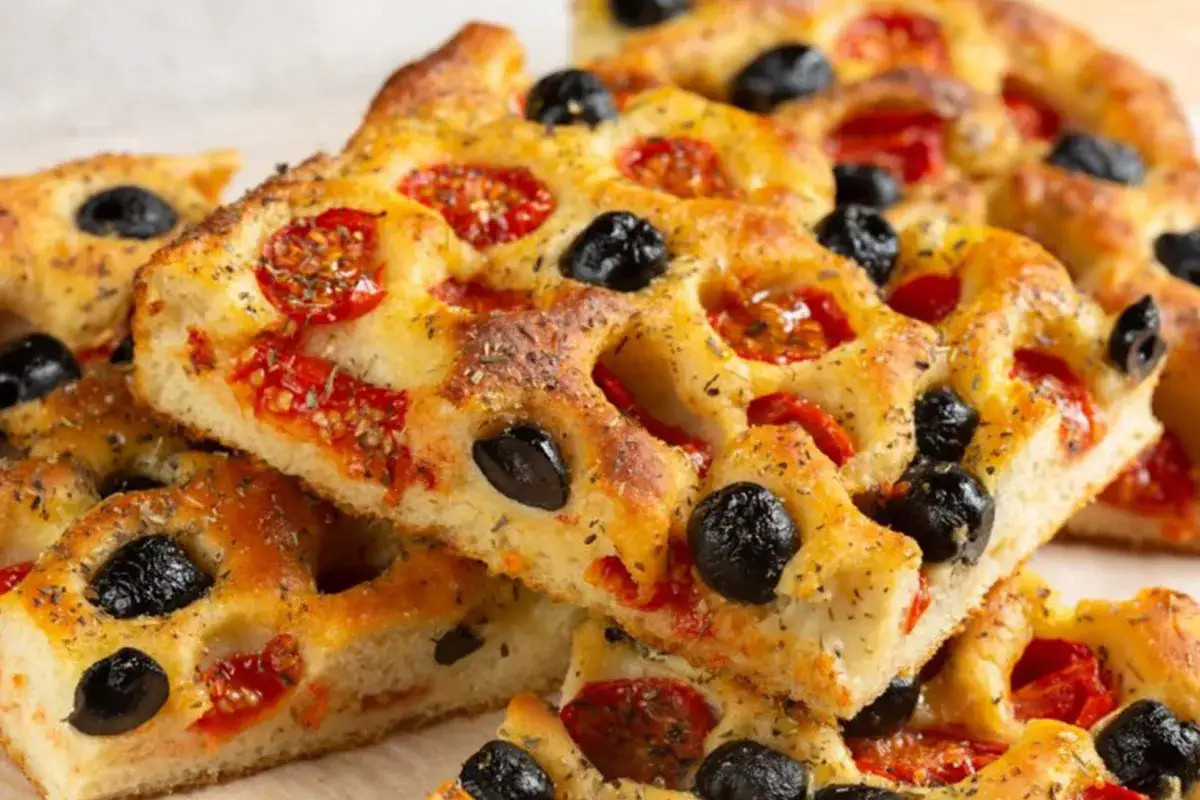 Pyszne, chrupiące bari jedzenie: focaccia z oliwkami i pomidorkami koktajlowymi, posypana ziołami. Idealna przekąska.