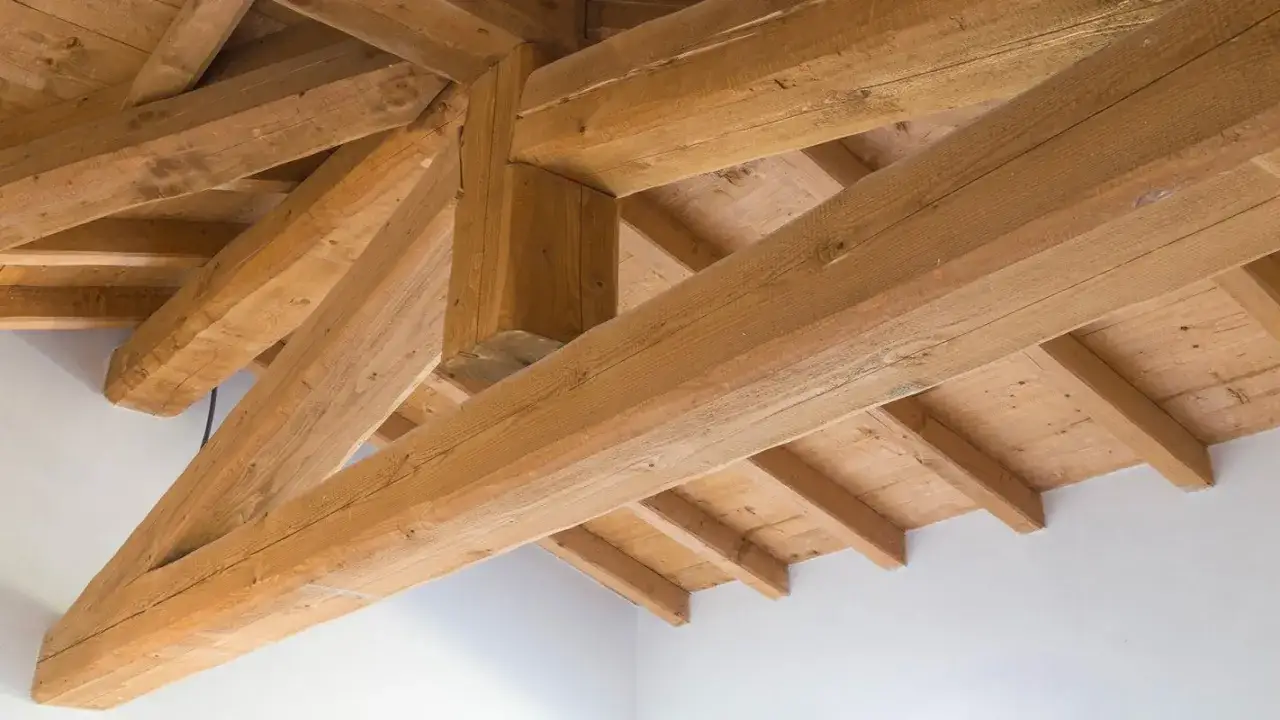Struttura a capriate in legno, con travi robuste e ben visibili, che evocano un senso di solidità e tradizione. Il legno sembra **impregnato** di storia e cura.