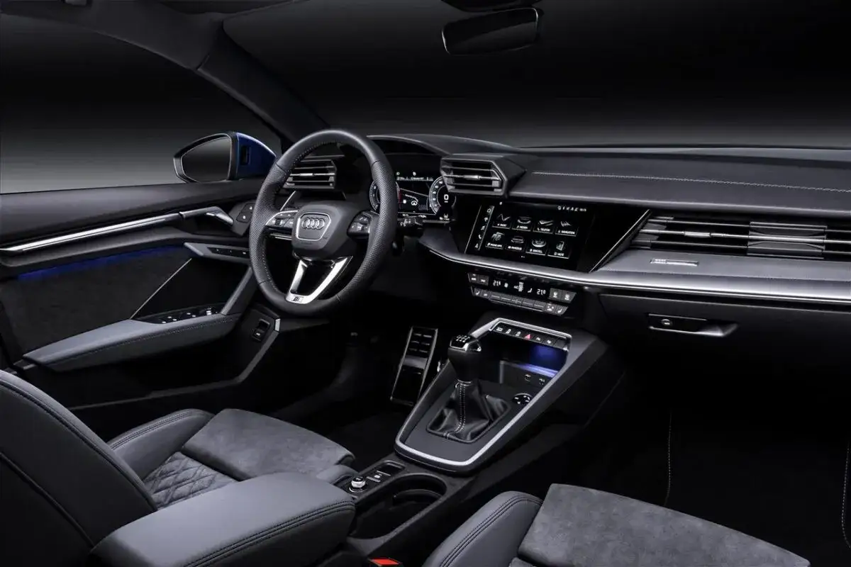 Interni moderni di un'Audi A3 con sedili in pelle, volante sportivo e ampio display touchscreen.