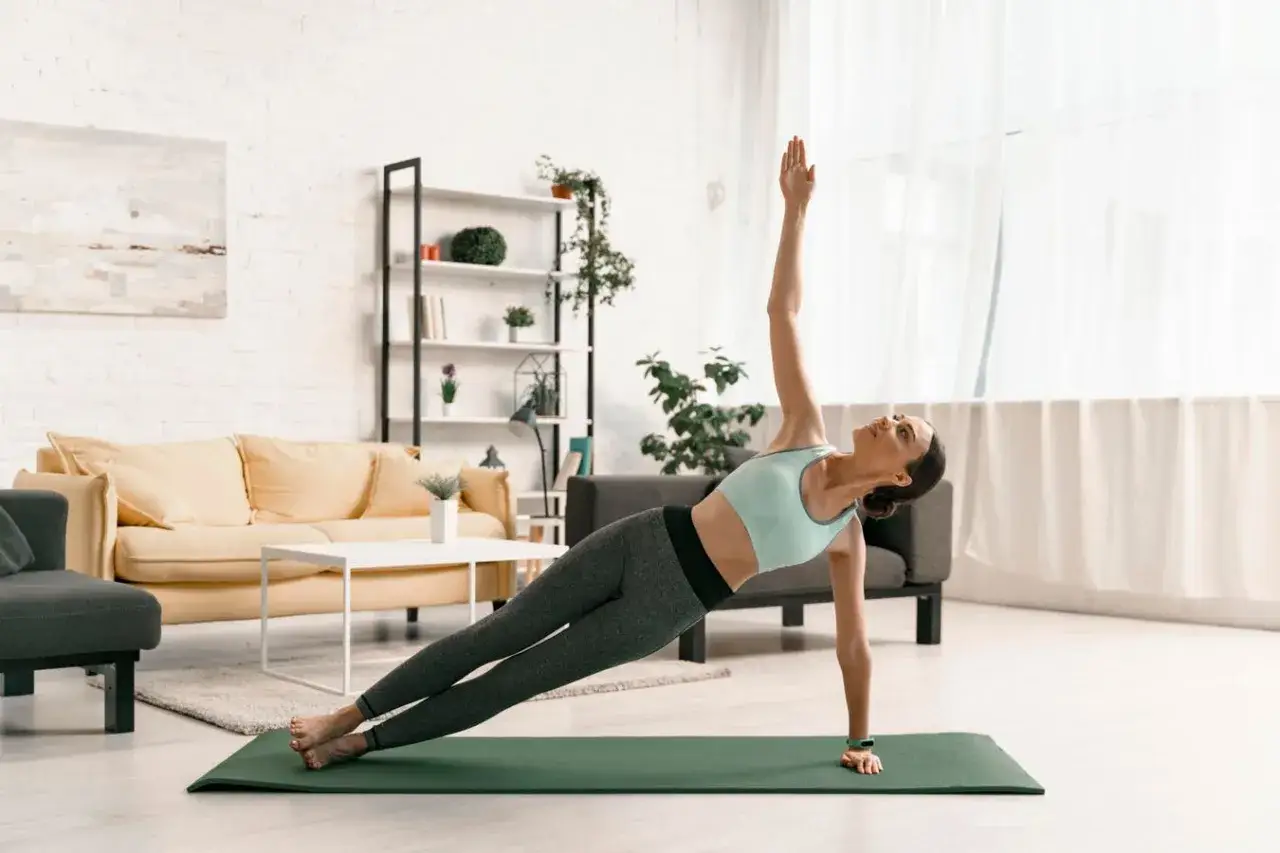 Donna in posa yoga Vasisthasana, mostrando i benefici di una pratica costante.