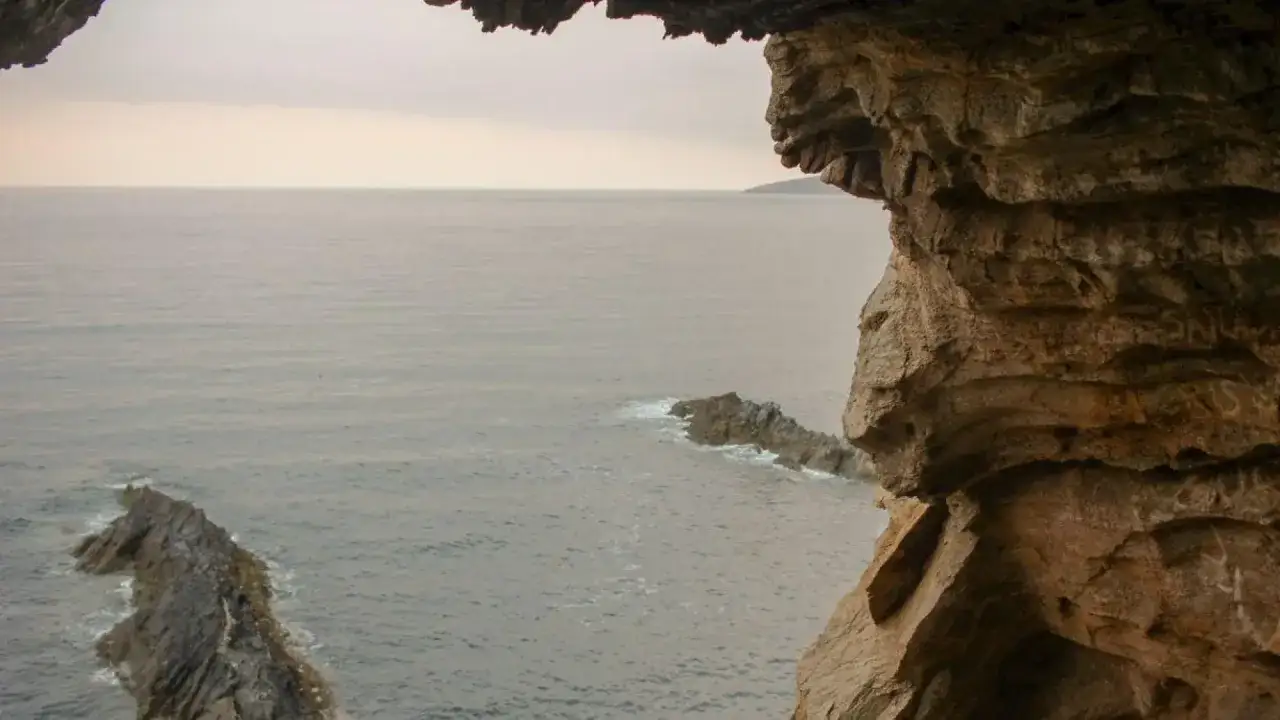 Vista desde la cova da serpe, con el mar grisáceo y rocas emergiendo.