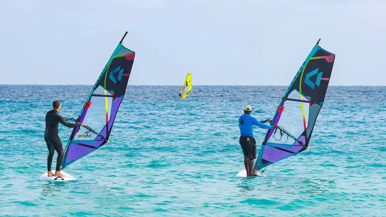Windsurfer auf dem Meer bei Santa Maria Sal. Zwei Windsurfer mit bunten Segeln, ein weiterer im Hintergrund.