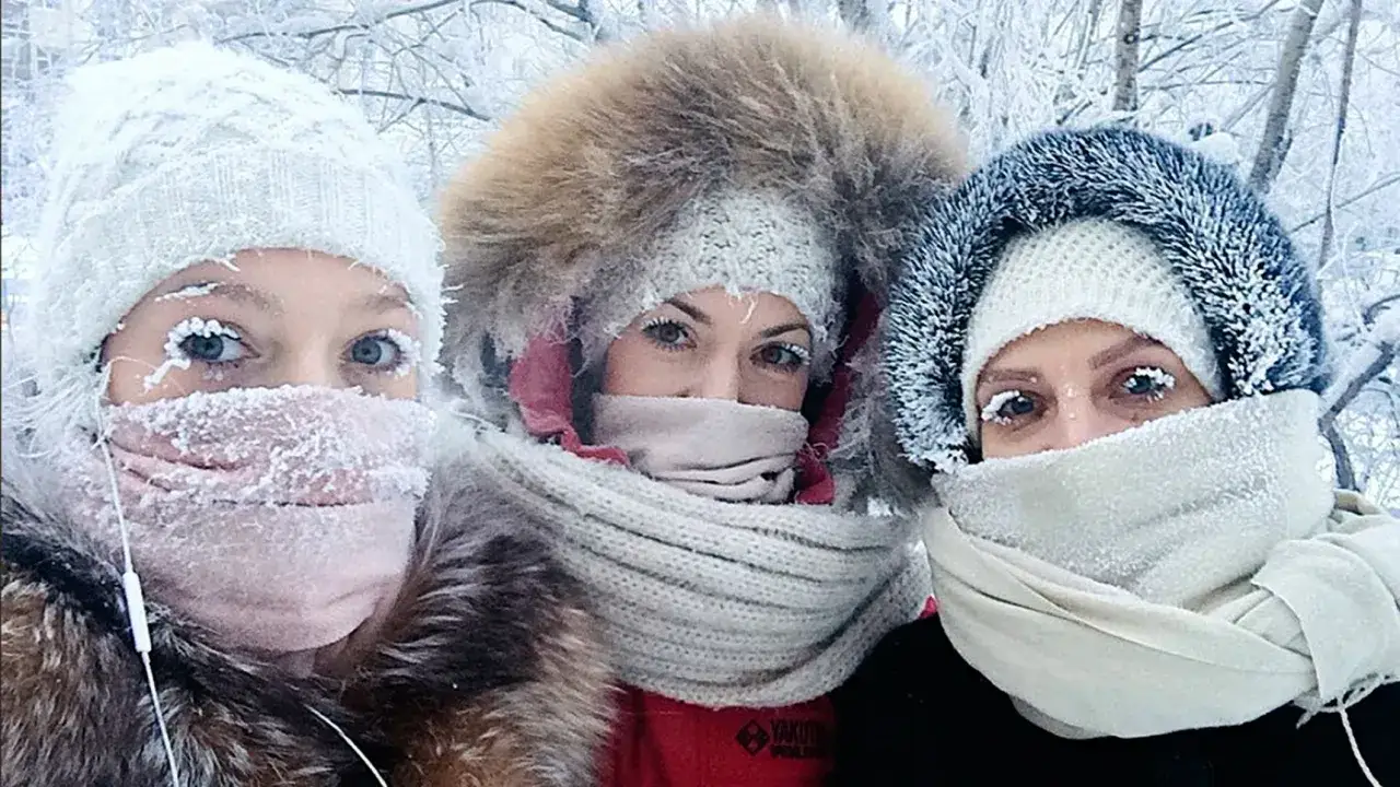 Trzy kobiety w czapach i szalikach, z lodem na rzęsach, doświadczają mroźnej Syberii zimą.