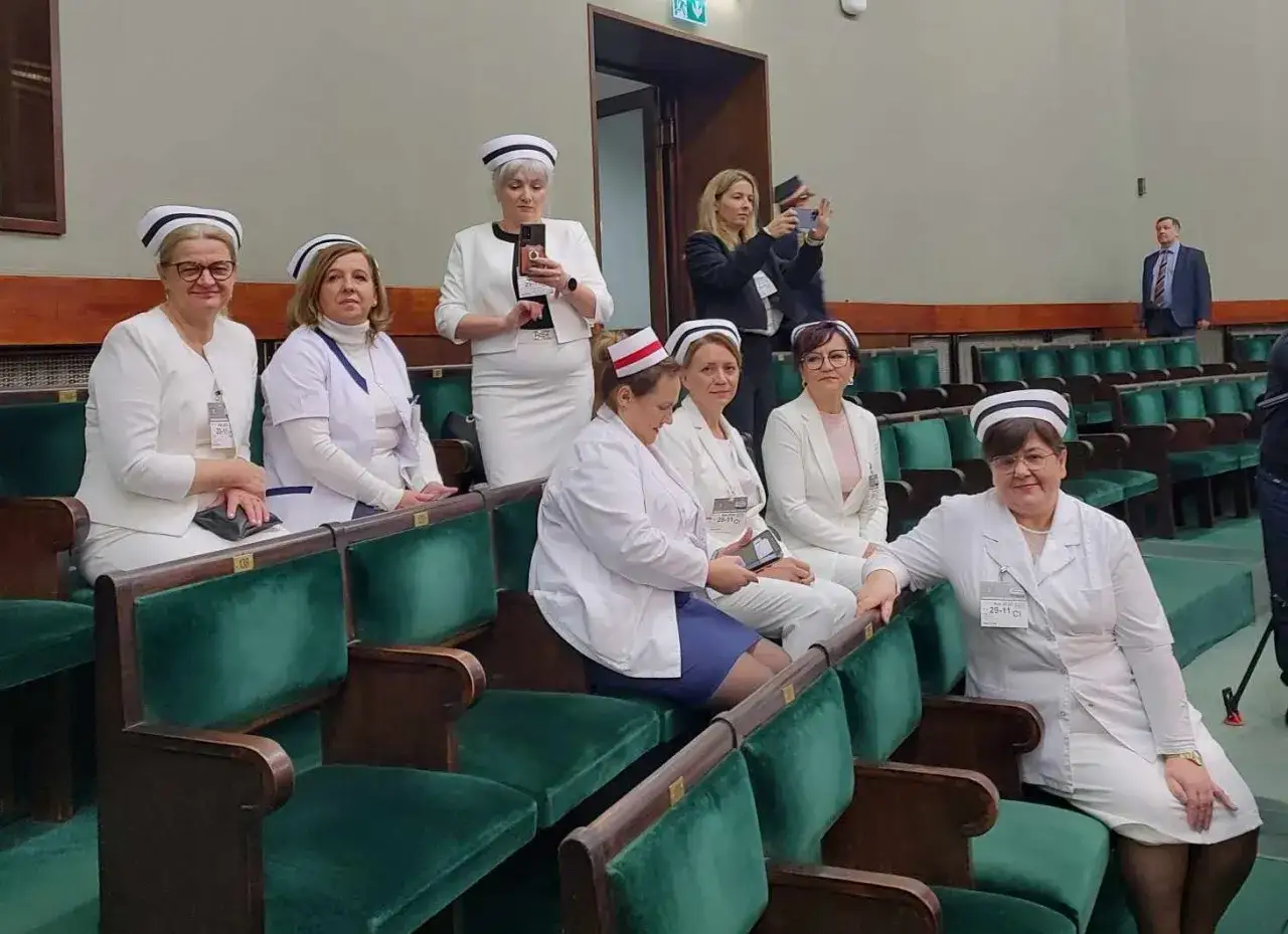 Pielęgniarki w strojach medycznych siedzą w sali sejmowej, czekając na wiadomości o podwyżkach.