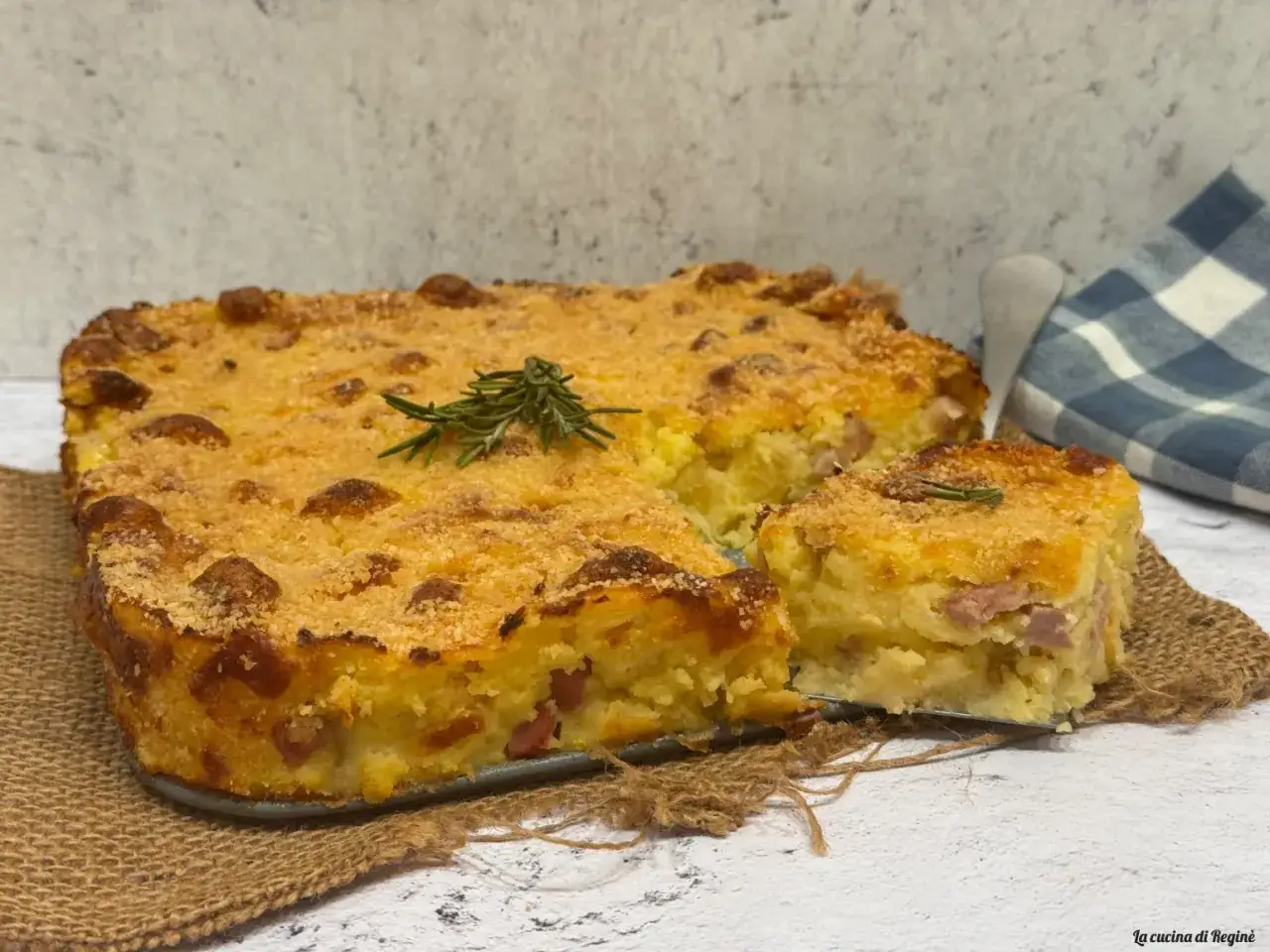 Gateau di patate dorato e croccante, con pezzetti di prosciutto e rosmarino, pronto per essere gustato.
