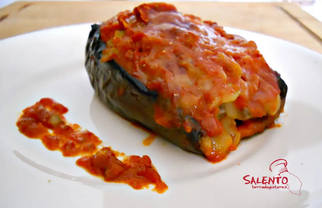 Melanzane ripiene pugliesi, un piatto gustoso e colorato, servito su un piatto bianco con un contorno di sugo.