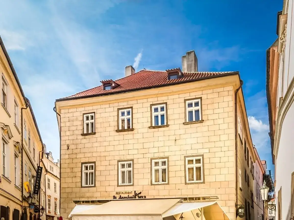 Urokliwe, kamienne budynki w **starym mieście Czech** pod błękitnym niebem. Restauracja z markizą zaprasza.
