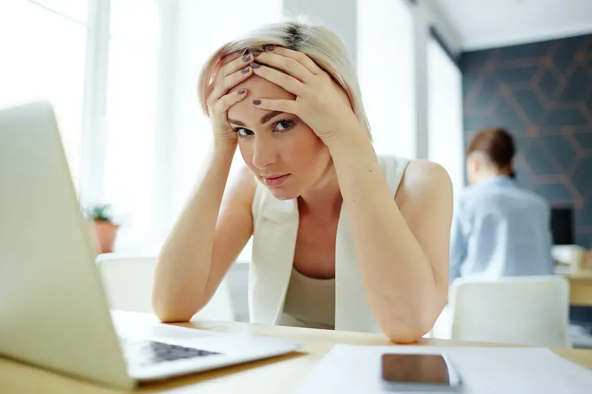 Zmartwiona kobieta przy laptopie, szukająca wzoru cofnięcia wypowiedzenia umowy o pracę z powodu ciąży.