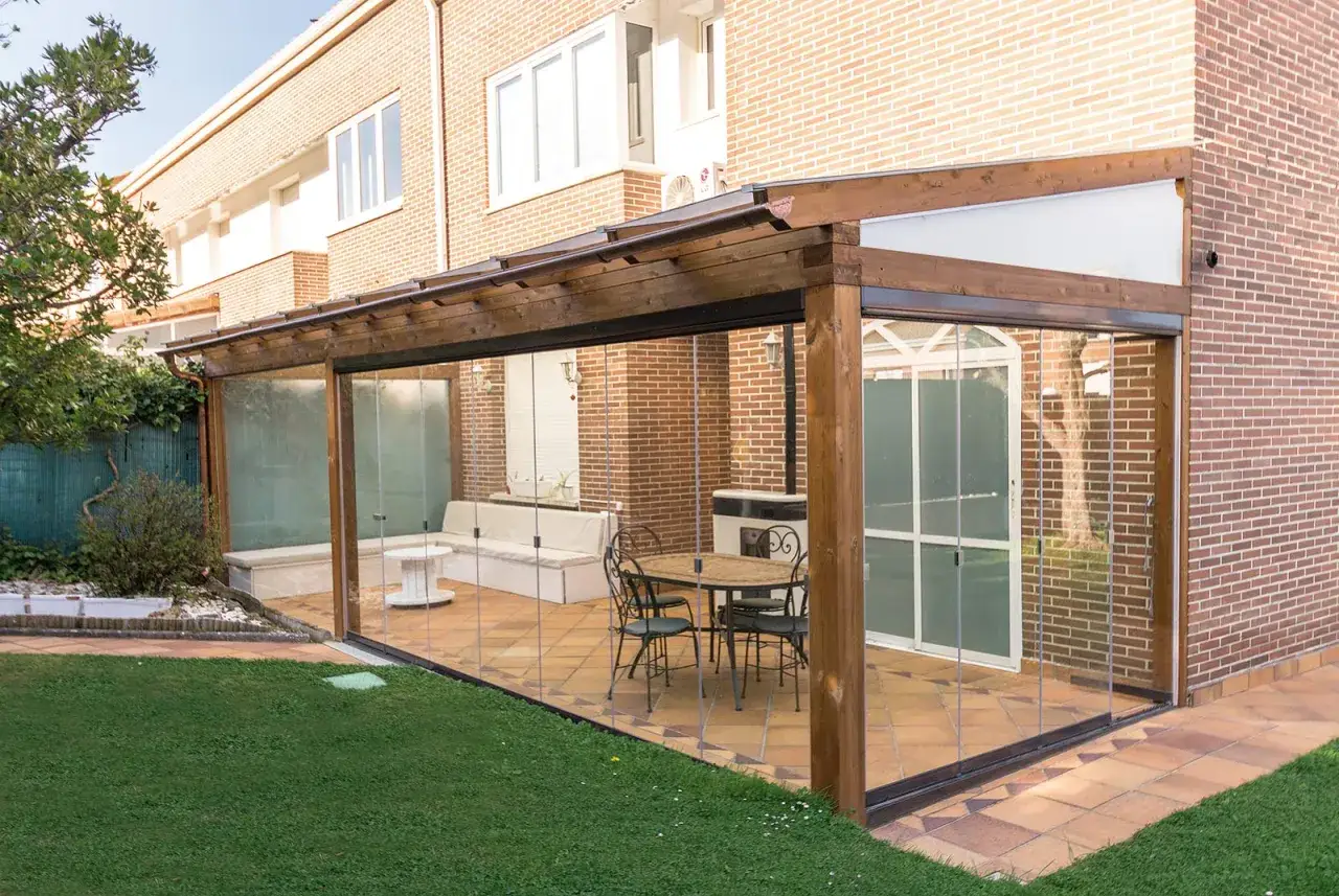 Porche acristalado precio: moderno espacio con mesa, sillas y sof&aacute;, ideal para disfrutar del jard&iacute;n todo el a&ntilde;o.