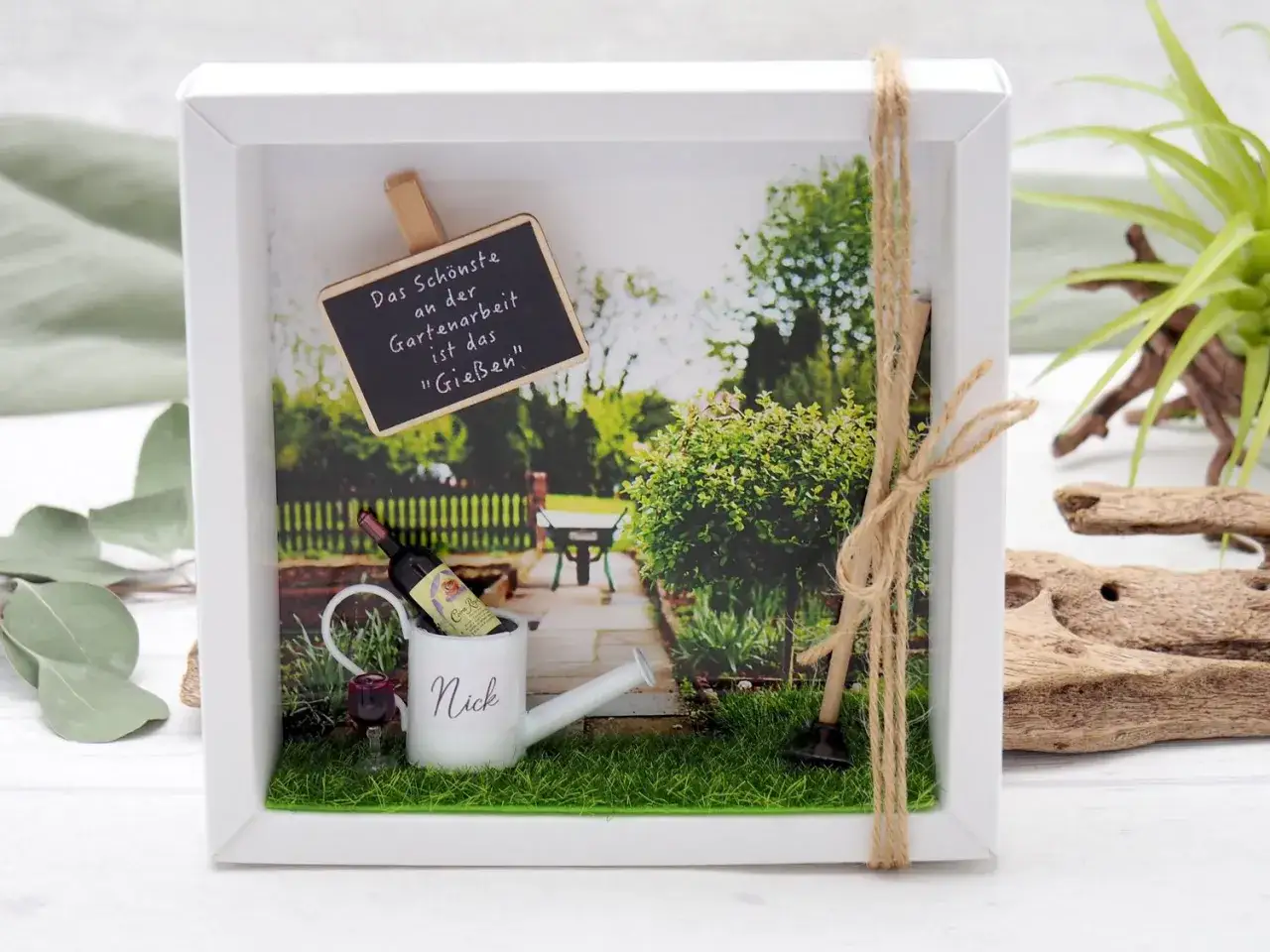 Ein liebevoll gestalteter Bilderrahmen mit Miniatur-Gie&szlig;kanne, Wein und Gartenger&auml;ten. Perfekt zum **gutschein basteln** f&uuml;r Gartenfreunde.