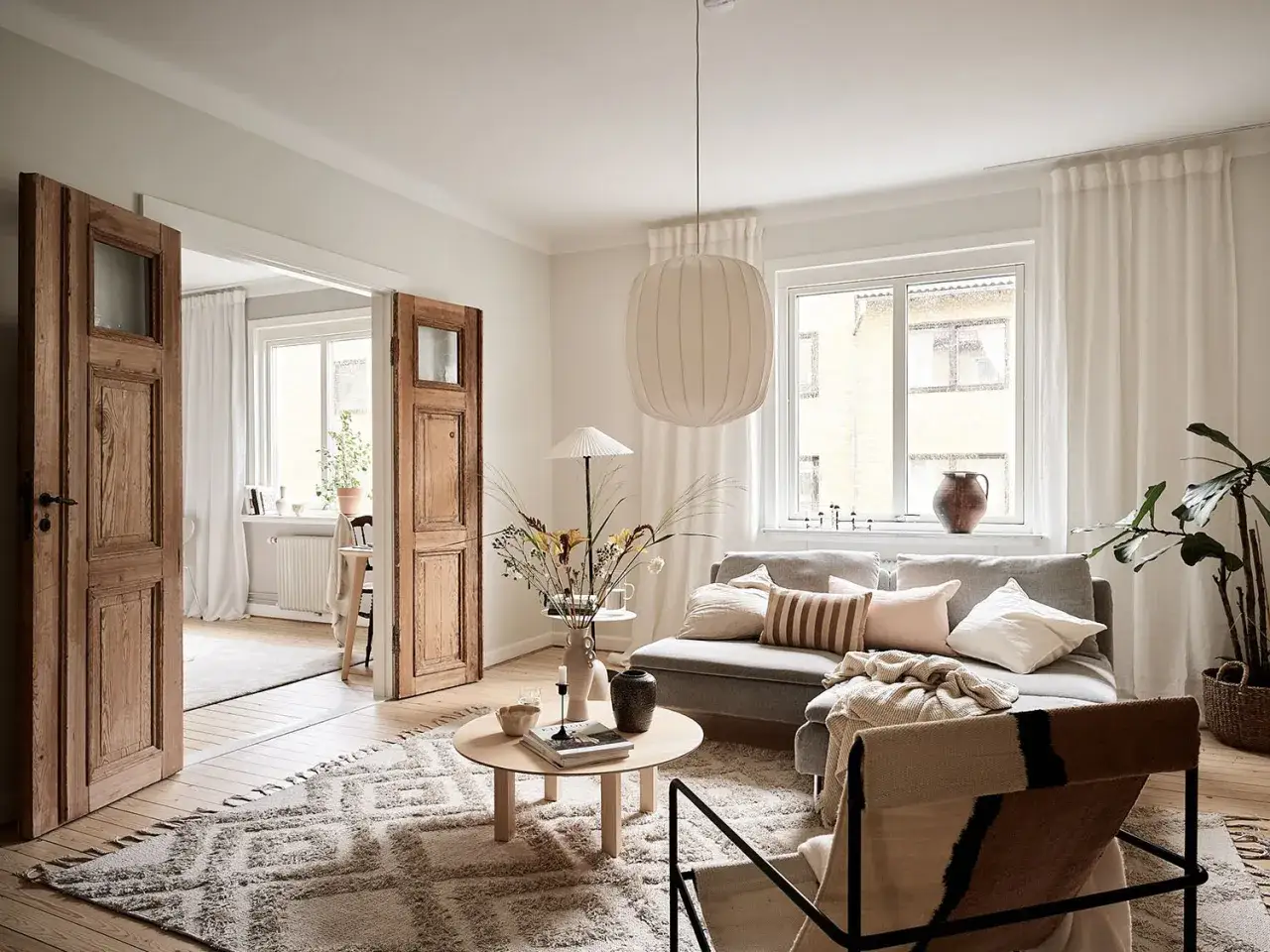 Gemütliches Wohnzimmer im **scandinavian style** mit Holztüren, Sofa, Teppich und Kaffeetisch.