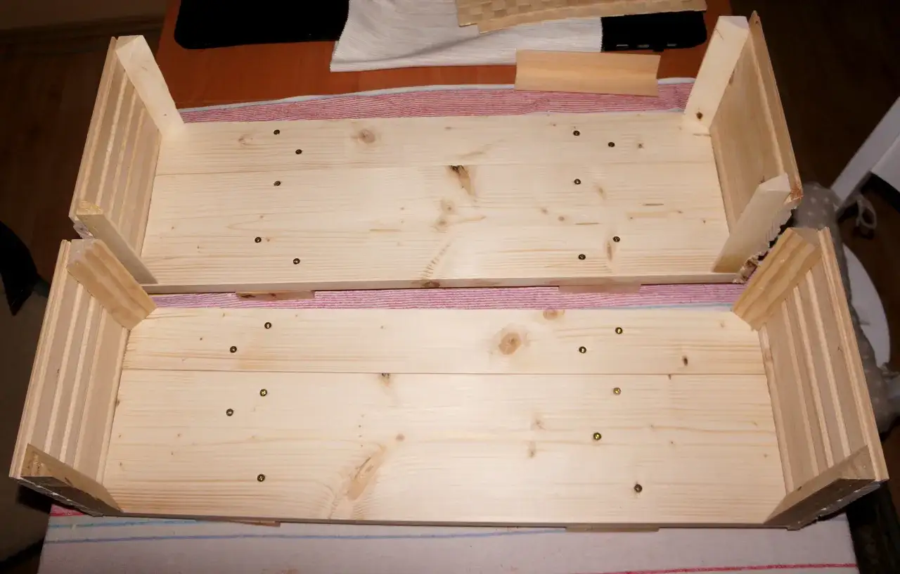 Dwa drewniane, niedokończone skrzynki, idealne do projektu diy flower box. Widać ślady po wkrętach i elementy konstrukcyjne.