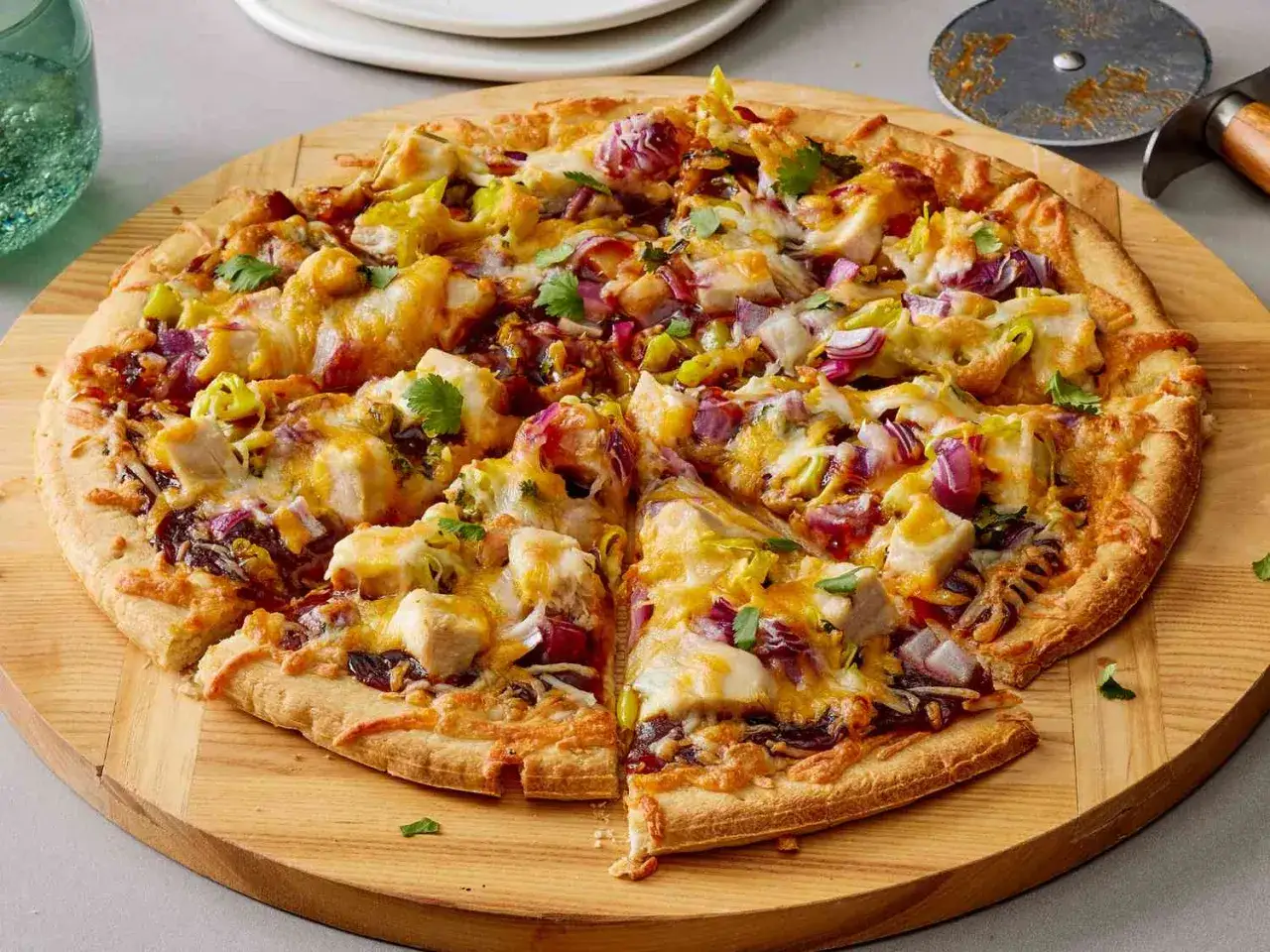 Apetyczna pizza z kurczakiem, czerwoną cebulą i serem, pokrojona na kawałki, gotowa do podania.
