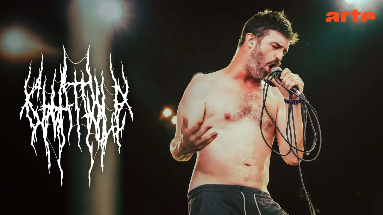 Un chanteur torse nu, micro en main, sur sc&egrave;ne. Le logo du groupe 
