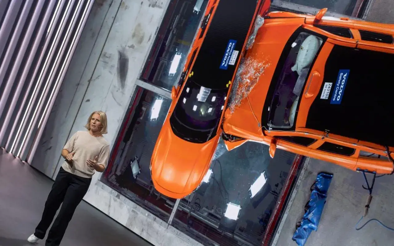 Kvinna presenterar krocktestresultat för Volvo Car AB. Två orangea bilar har krockat.