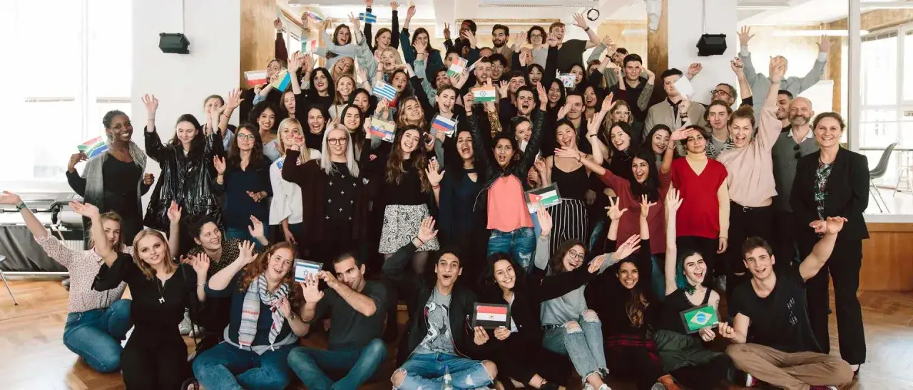 Internationale Gruppe feiert Vielfalt in Berlin. Studierende mit Flaggen zeigen stolz ihre Herkunft. Modemanagement-Kurs in Berlin.