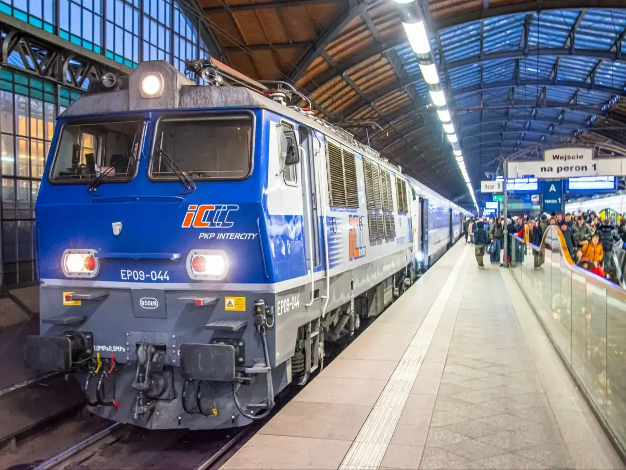 Niebieski pociąg PKP Intercity EP09-044 na peronie. Pasażerowie czekają na podróż z Olsztyna do Wrocławia.