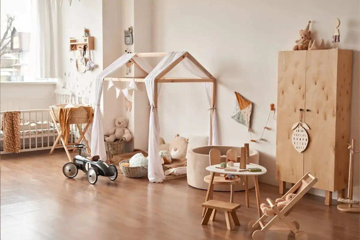 Habitación infantil con cuna, tienda de campaña de madera, peluches y juguetes. Un espacio ideal para el **método Montessori en casa**, fomentando el juego y el aprendizaje.