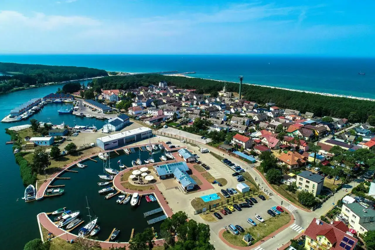 Widok z lotu ptaka na port w Dziwnowie, gdzie cumują liczne jachty i łodzie. W tle widać miasteczko i morze. To jedne z wielu dziwn&oacute;w atrakcji.