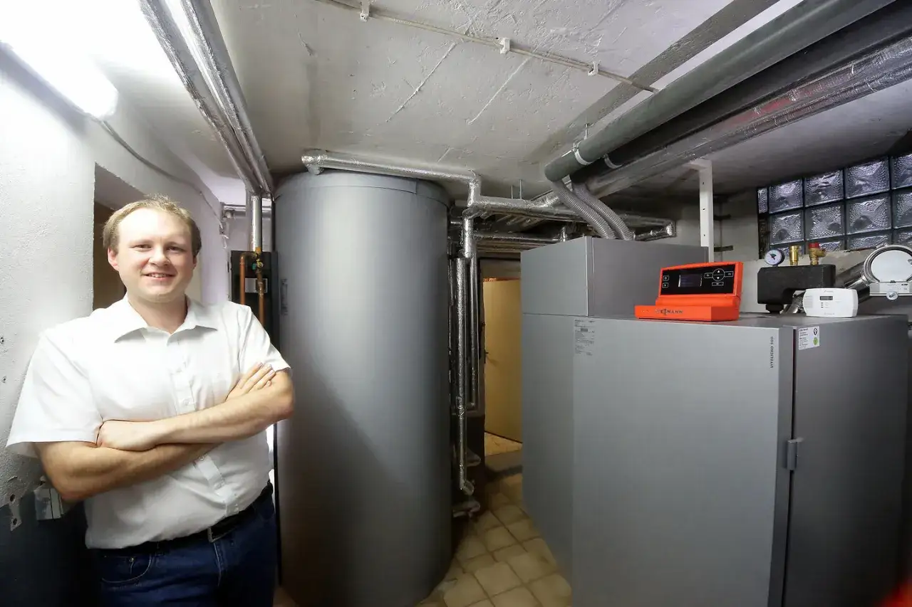 Mann vor Heizungsanlage. Informiert sich, was kostet eine Pelletheizung mit Einbau?