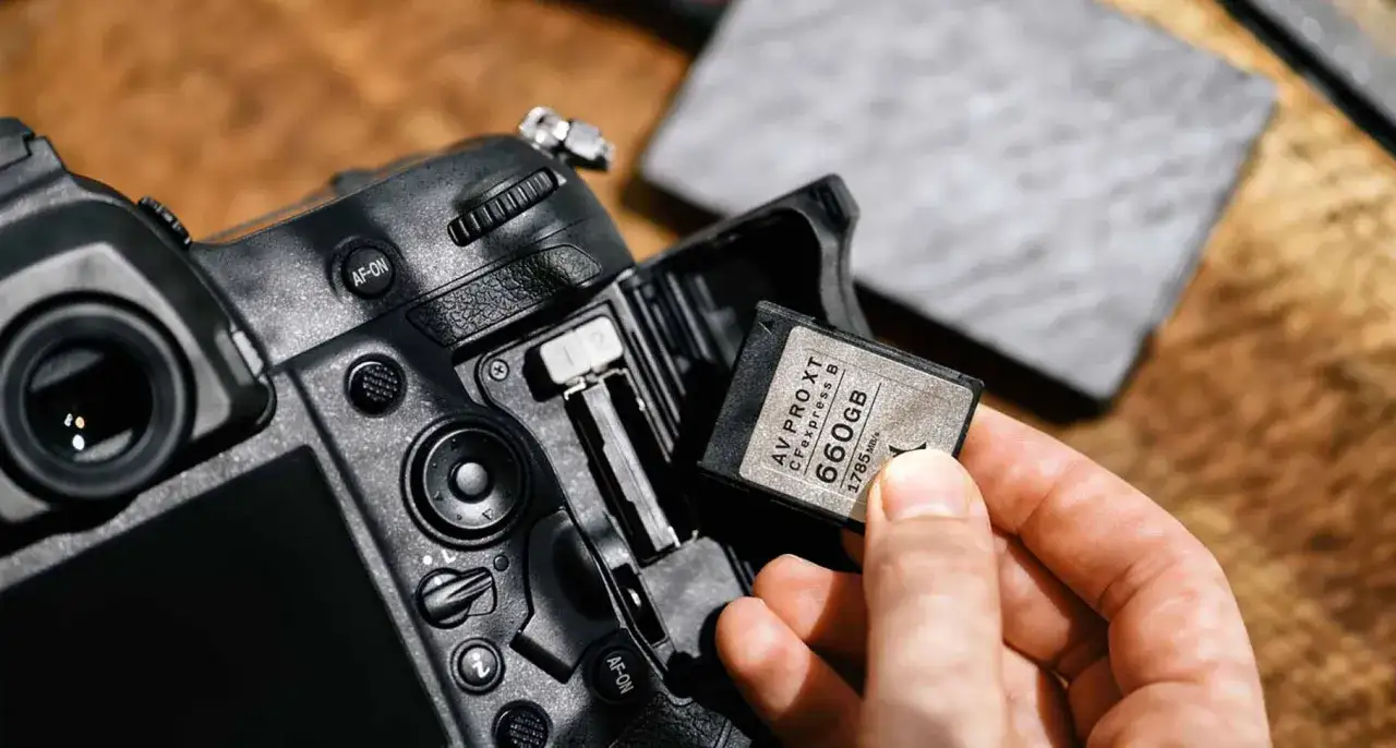 Dłoń wkłada kartę CFexpress B 660GB do aparatu, gotowa do szybkiego zapisu.