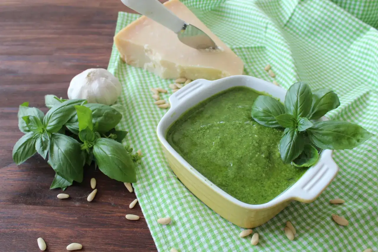 Pesto genovese frullatore pronto in un piatto, con basilico fresco, pinoli, aglio e parmigiano.
