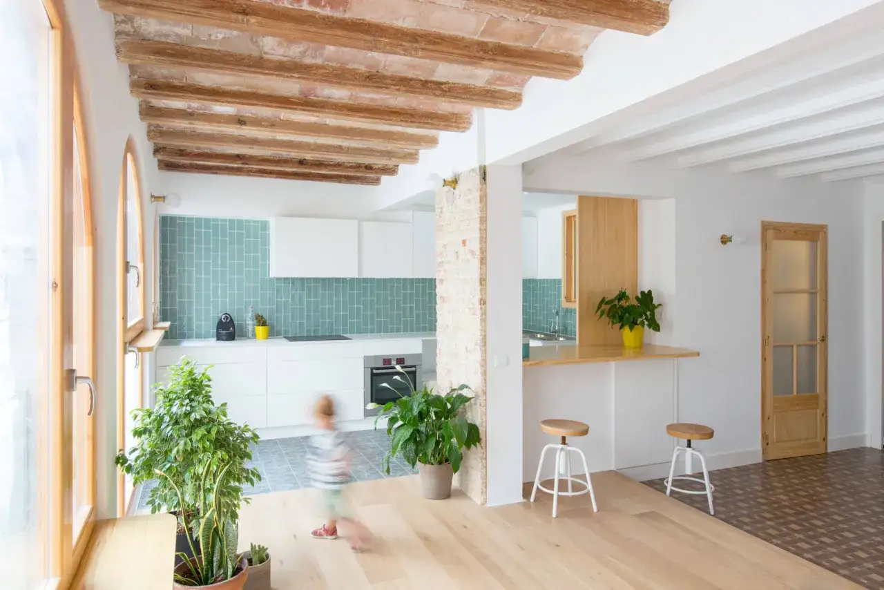 Cocina estilo mediterráneo con vigas de madera expuestas, azulejos turquesas y una barra de desayuno.