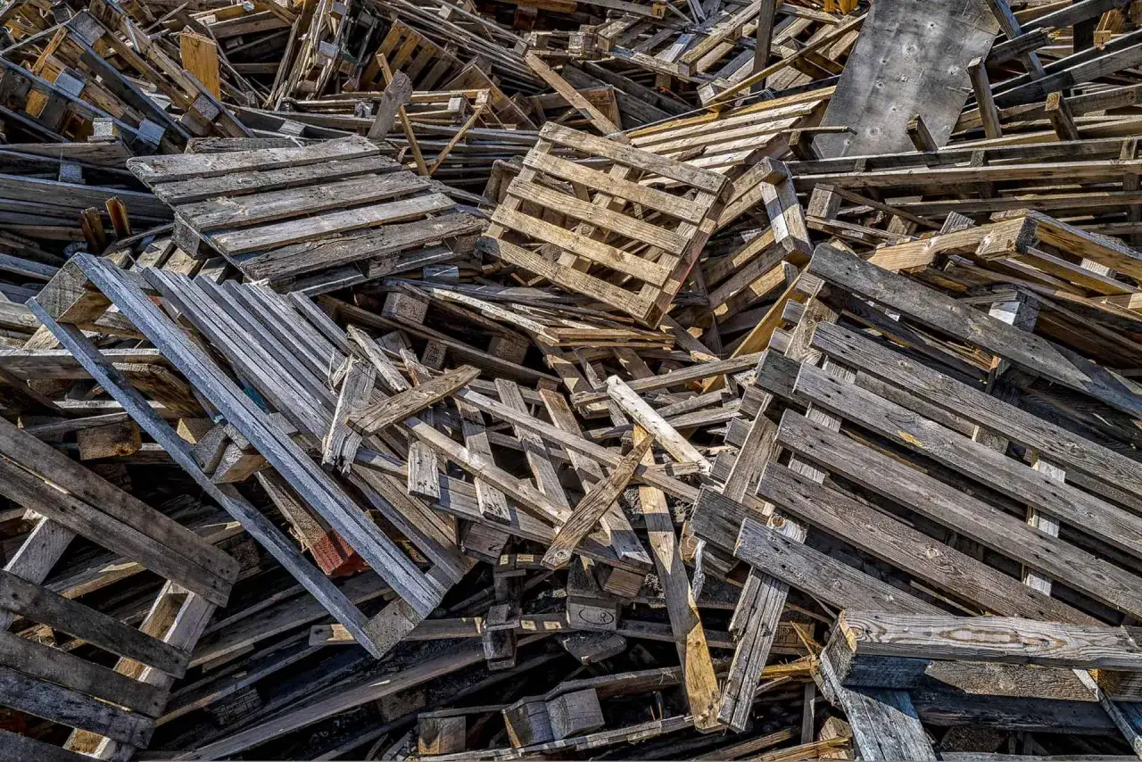 Stos starych, drewnianych palet. Zastanawiasz się, gdzie wyrzucać drewno? Te palety mogą być poddane recyklingowi lub wykorzystane jako paliwo.