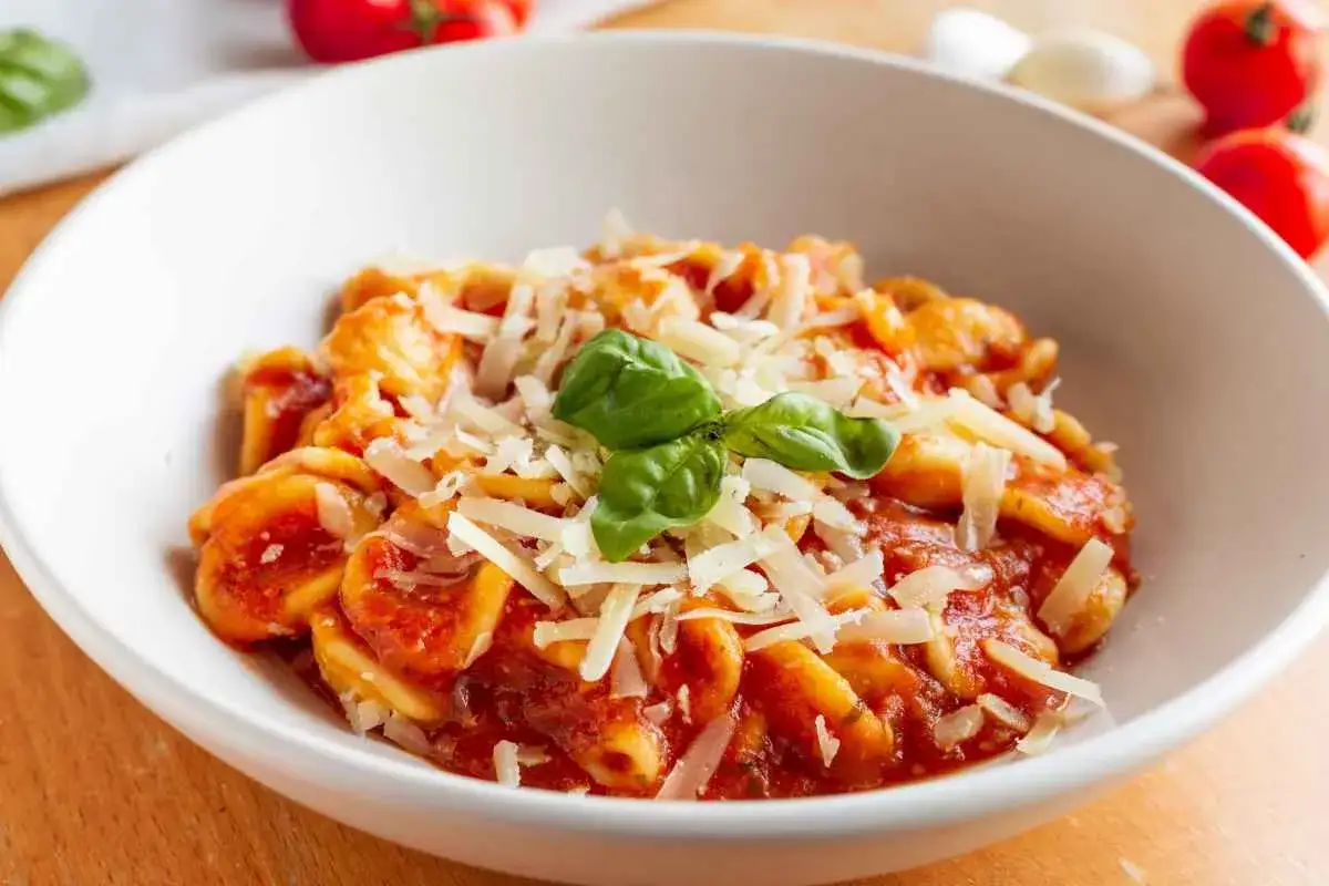 Orecchiette pugliesi con sugo rosso, parmigiano grattugiato e basilico fresco. Un piatto che sa di casa e tradizione.