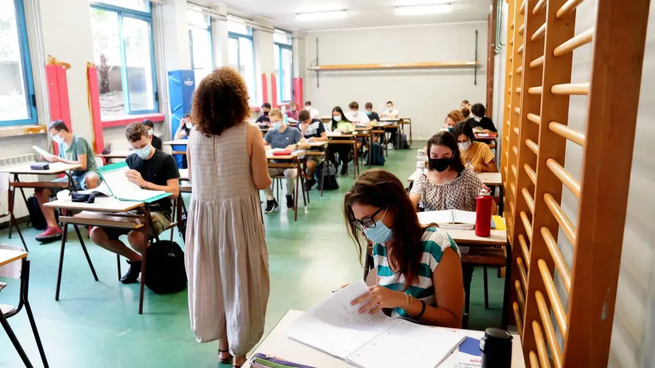 Studenti in classe con mascherine, alcuni sembrano concentrati, altri forse provano un po' di paura della matematica.