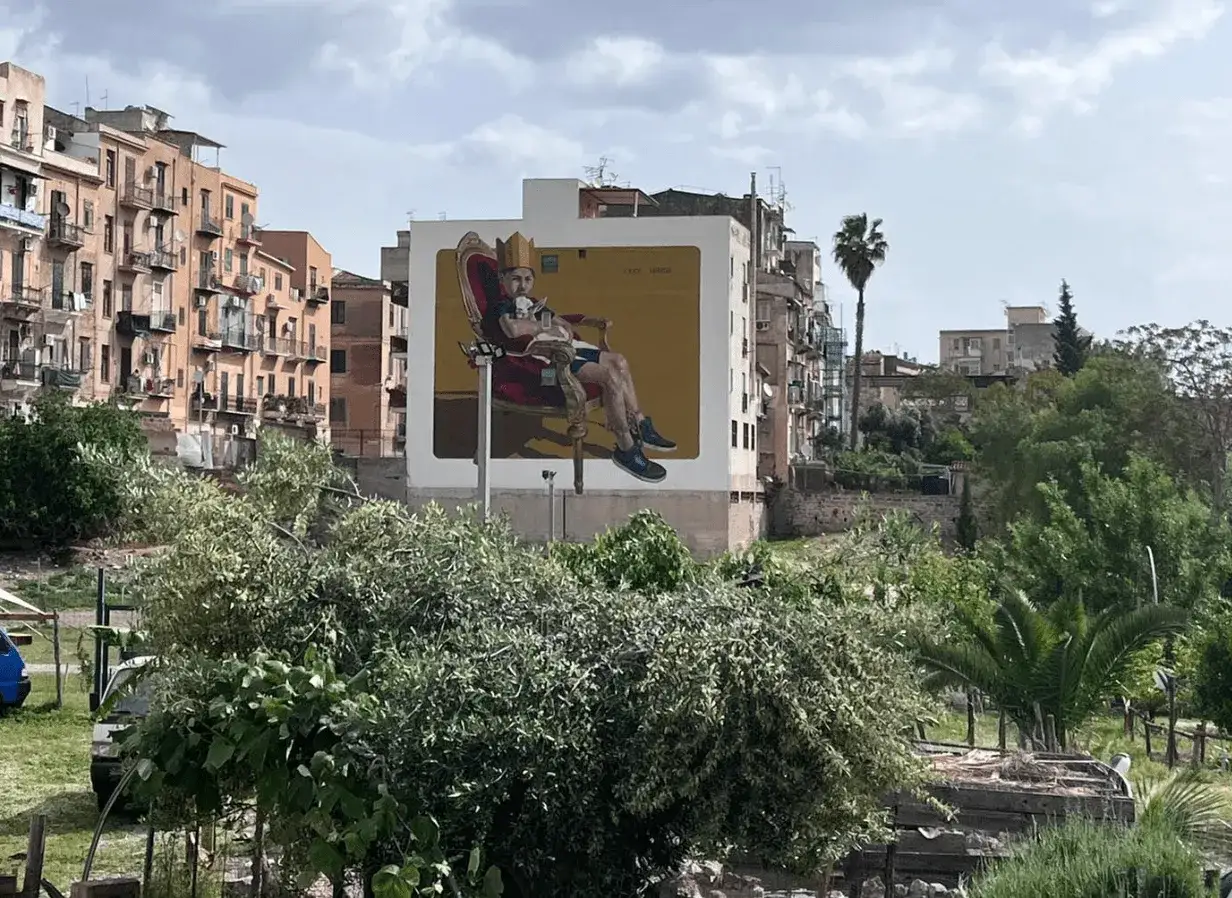 Murale di Danisinni a Palermo: un re su un trono rosso, con corona e un cagnolino.