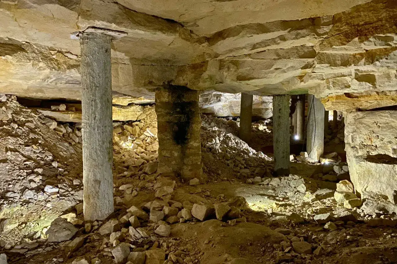 Podziemne korytarze krzemionkowskiego regionu prehistorycznego górnictwa krzemienia pasiastego, wsparte kamiennymi filarami, z rumowiskiem skalnym.