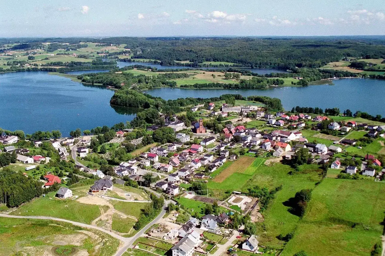 Malownicze jeziora i urokliwa wieś, idealne na Kaszuby na weekend. Zielone wzgórza, domy z czerwonymi dachami i spokojna tafla wody.