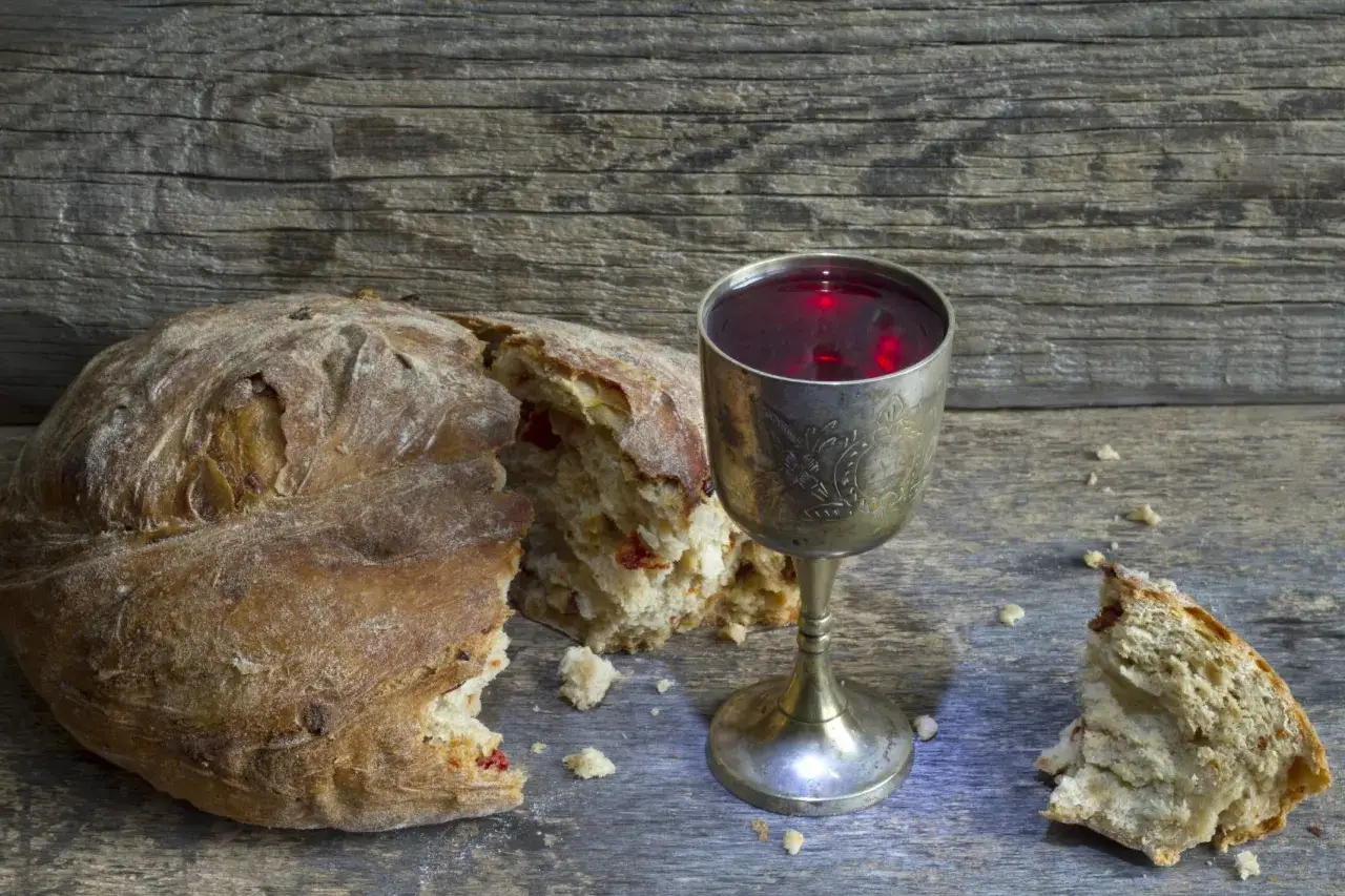 Ein zerbrochenes Brot, ein Kelch mit rotem Wein. Das Brot als Symbol f&uuml;r Gemeinschaft und Opfer.