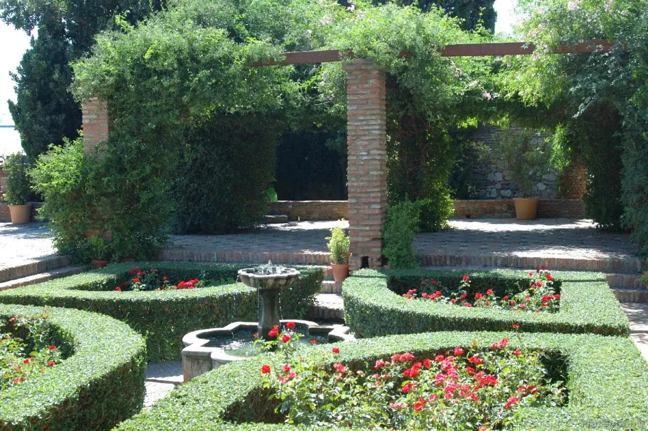 Jard&iacute;n con fuente y setos en M&aacute;laga. Una puerta oscura de vegetaci&oacute;n invita a explorar este rinc&oacute;n id&iacute;lico.