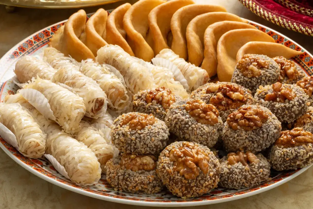 Assortiment de pâtisseries orientales, dont des makrouts et des gâteaux aux noix, parfaits pour accompagner une recette de corne de gazelle.