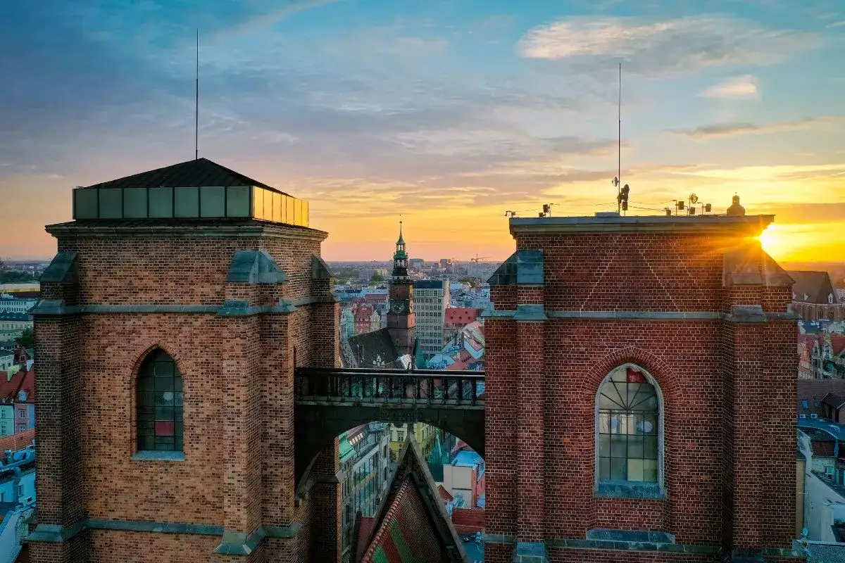 Mostek pokutnic we Wrocławiu, łączący wieże kościoła św. Elżbiety, oświetlony zachodzącym słońcem.