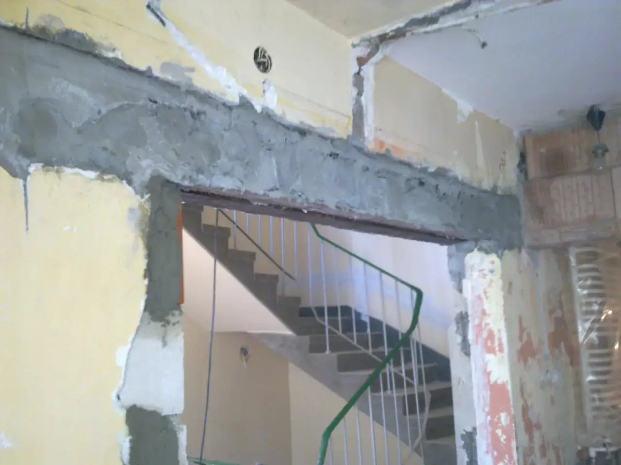 Remontowany otwór w ścianie, widoczna betonowa nadproże i schody. Jak rozpoznać ścianę nośną w starym domu? Grubość i materiał to klucz.